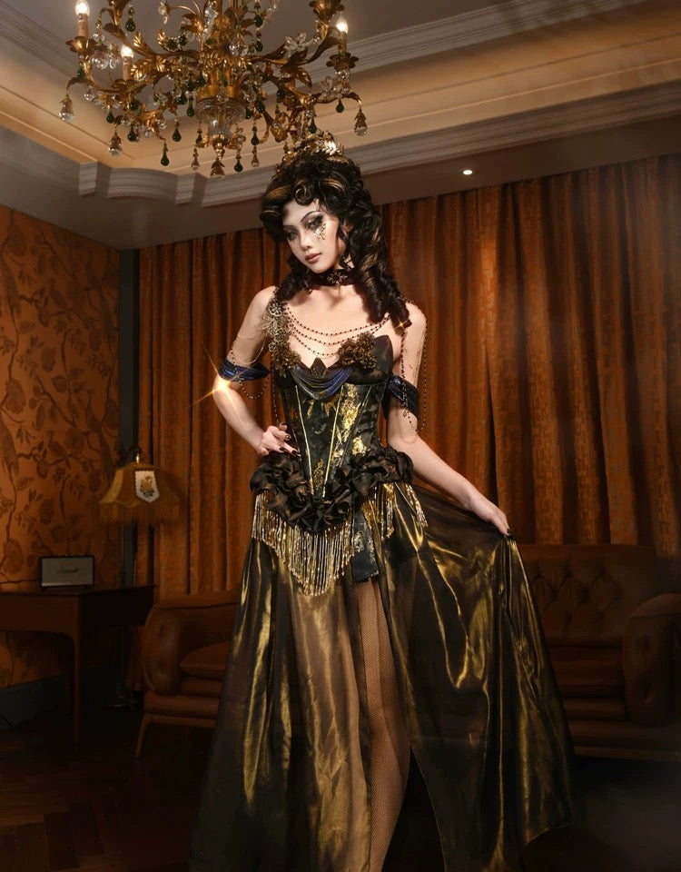 Woman in a gold and black dress standing in an opulent room with chandelier and curtains.