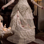 girl wearing a detailed Victorian-era gown in a dimly lit room.