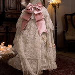 Vintage-style dress with a large pink bow in an elegant room setting.