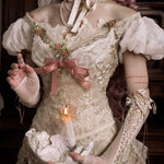 girl in an vintage floral bridal dress holding a candle, with a dark background. Gothic fashion for halloween wear.