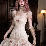 woman in a vintage-style lace white dress with pink ribbon details in a dimly lit room.