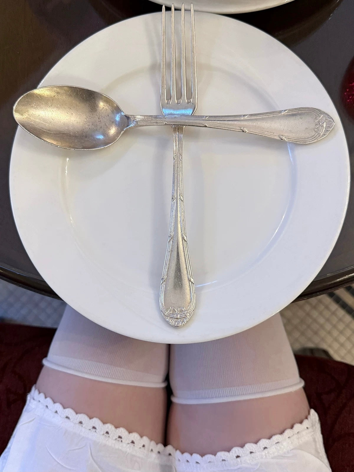 Person wearing white underwear with a white plate, spoon, and fork arranged in a manner resembling underwear.