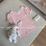 Pink babydoll top with lace details and a plush bunny toy on a textured surface.
