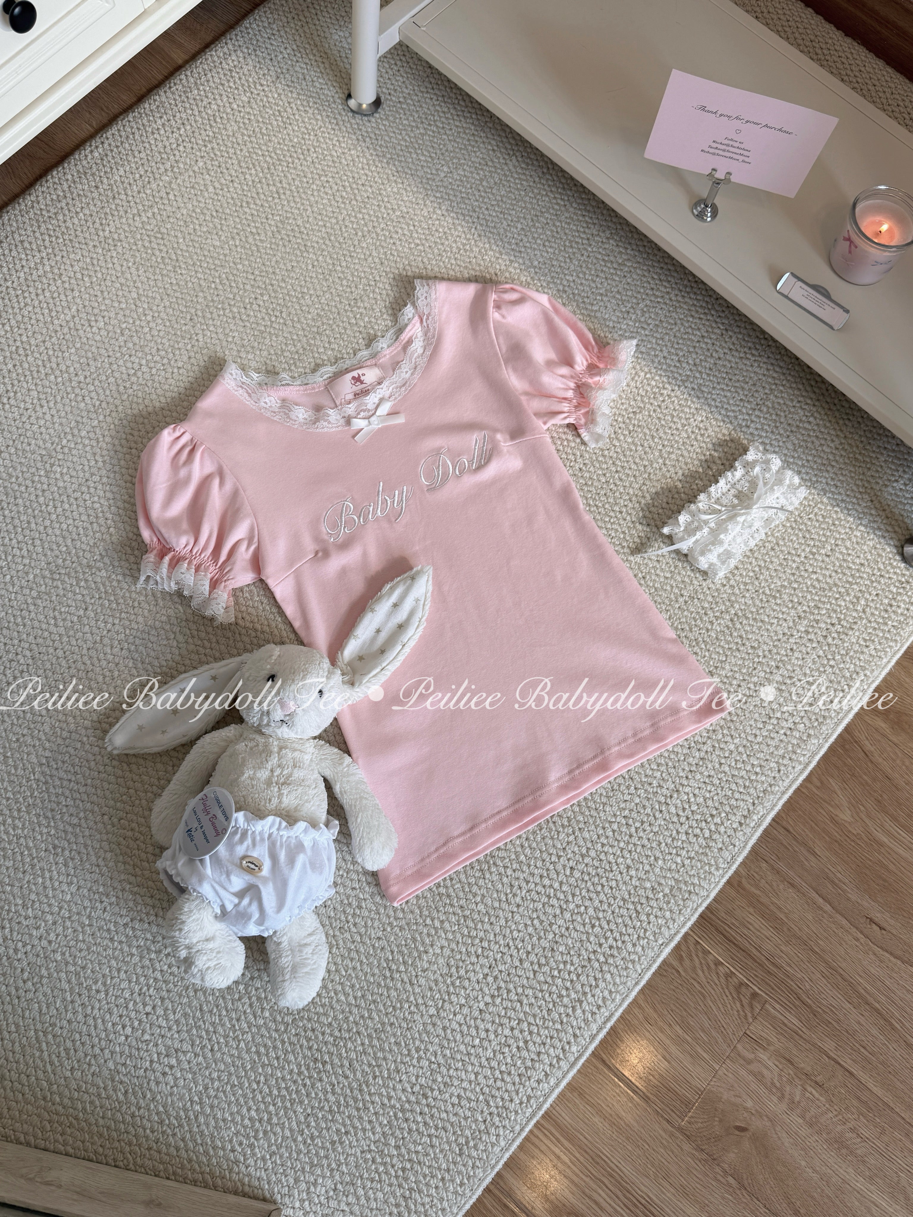 Pink babydoll top with lace details and a plush bunny toy on a textured surface.