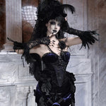 Person in a dark, ornate costume with gothic design against a marble wall.