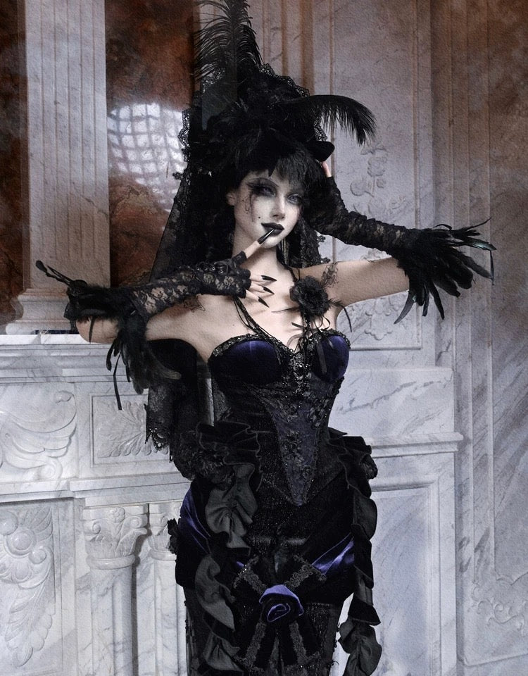 Person in a dark, ornate costume with gothic design against a marble wall.
