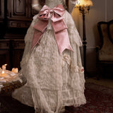 Vintage-style dress with a large pink bow in an elegant room setting.