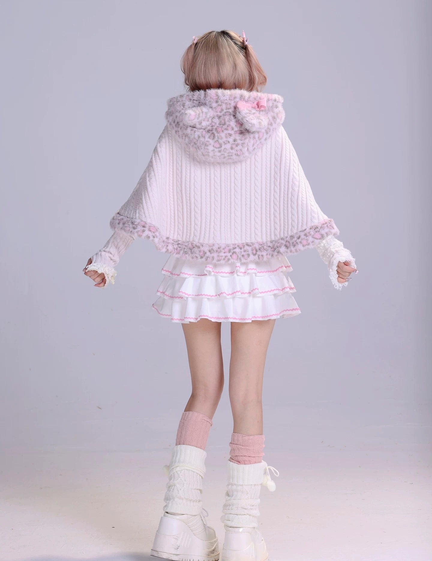 Girl wearing a white and pink fluffy faux fur cape with a matching pastel white mini skirt and leg warmmers