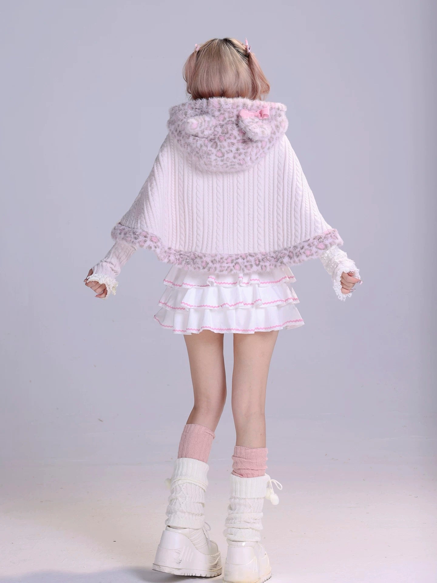 Girl wearing a white and pink fluffy faux fur cape with a matching pastel white mini skirt and leg warmmers