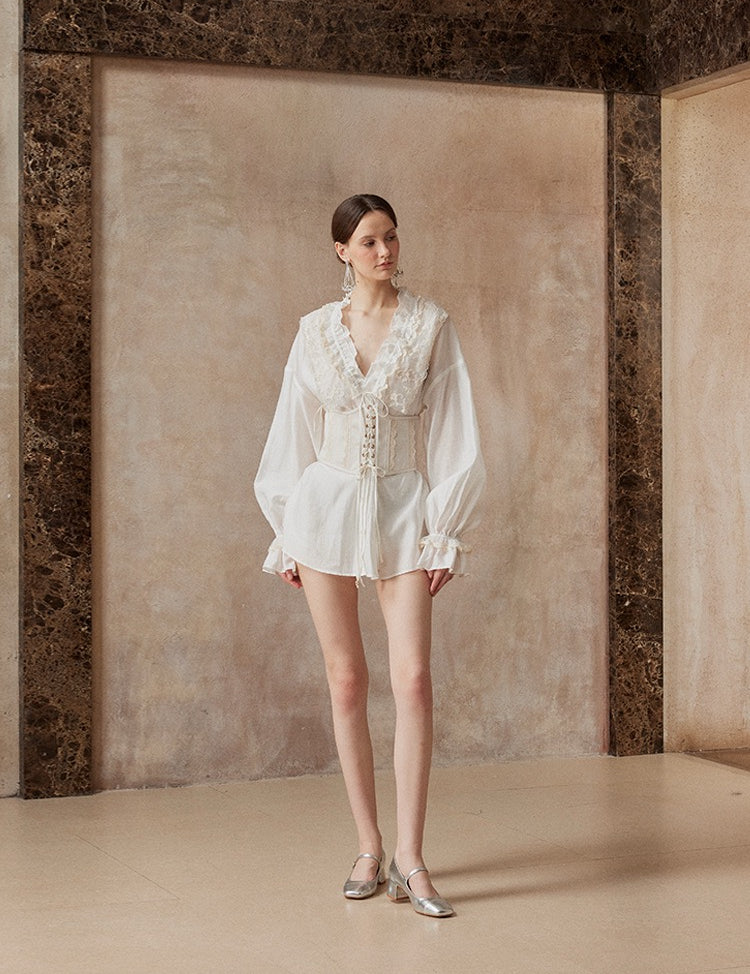 Woman wearing a white outfit standing against a textured wall.