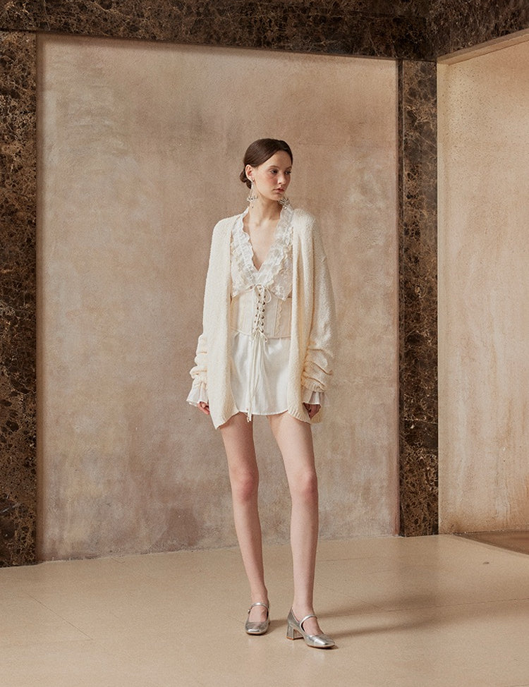 Woman wearing a white outfit standing against a textured wall.