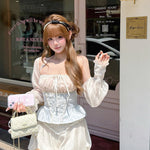 Woman in a white outfit standing outside a store with a pink bag.