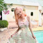 Woman in a floral dress standing by a pool with decorative elements.