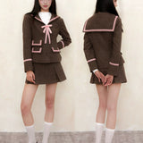 School girl wearing a brown school uniform with pink accents, standing against a plain background.